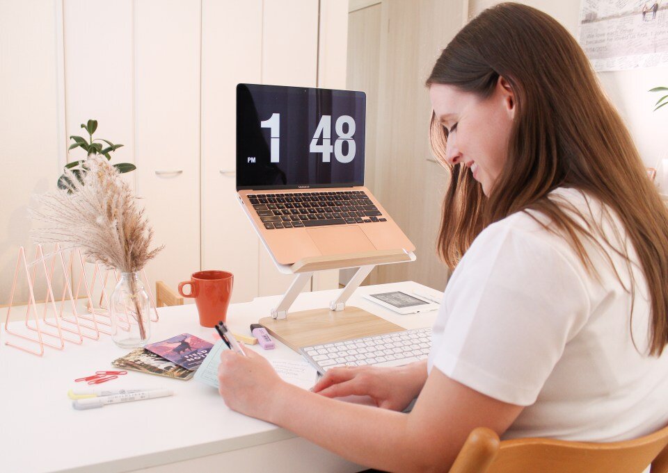 woman smiling while writing notes at her desk